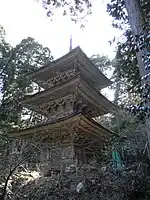 Une pagode en bois à deux étages dans une forêt.