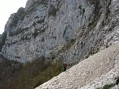 Randonneur franchissant des éboulis au pied d'une montagne.