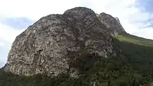 Crête d'une montagne vue en contre-plongée avec une grotte à sa base.