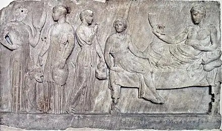 Relief en marbre, représentant Dionysos (à droite) et des acteurs tenant des masques (à gauche), voué au dieu après une représentation. Le Pirée, v. 400 av. J.-C. Musée national archéologique d'Athènes.