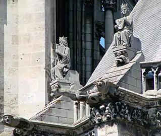 Une série de rois musiciens trônant au sommet des contreforts de la chapelle axiale, au chevet de la cathédrale, juste derrière le chœur. De longues gargouilles sont visibles en contrebas.
