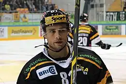 Photographie couleur d’un hockeyeur, en buste, le regard tourné vers l’objectif