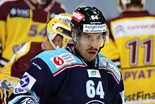 Homme, de buste, portant un équipement de hockey sur glace, maillot à dominante bleue marine