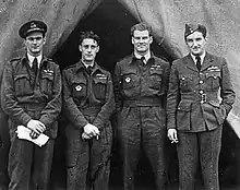 Photo en noir et blanc de quatre hommes en uniforme, regardant le photographe.