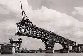 Photographie en noir et blanc de la construction du pont de Nankin, avec une charpente métallique inachevée