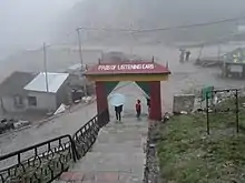 Portail rouge, vert et jaune en forme d'arche, avec une inscription blanche sur la partie supérieure, au pied d'un escalier.