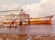 Bateau en train d'être chargé de phosphate au moyen de structures en cantilever.