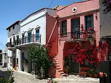 photographie : une rue avec deux maisons blanches et une maison rose