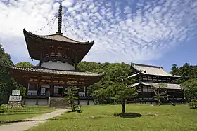 Photographie d'une pagode à deux étages et d'un autre bâtiment, au milieu d'un jardin épuré.