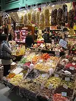 Une boutique du marché exposant de nombreux produits dont des fruits confits et des pâtes.