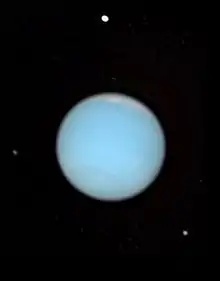 Photo de Neptune entourée de quatre de ses lunes, visibles en blanc.