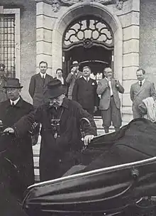 Oskar aide son père à monter dans la voiture qui l'emmène à partir de l'hôtel particulier de Neudeck sur le perron duquel on aperçoit la femme d'Oskar et divers hommes politiques