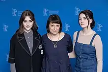 Trois femmes de face, posant devant un fond bleu.