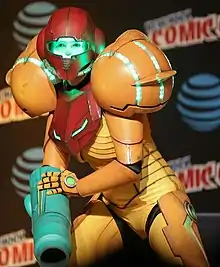 Femme dans un costume de Samus Aran de couleur jaune et rouge (cosplay).