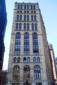 Photographie de la façade d'un bâtiment. La maçonnerie est percée de fenêtres au sommet en arche mais on peut distinguer plusieurs tailles de vitrages en largeur et en hauteur.