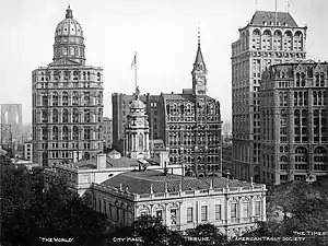 Photographie d'ensemble de plusieurs gratte-ciel de style néoclassique entourant un bâtiment de plus petite taille et de style colonial