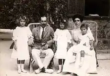 Photographie en noir et blanc d'un couple assis sur une terrasse et entourée de trois petites filles.