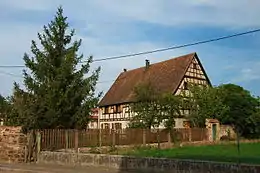 Fermemaison d'habitation (façades, toitures avec charpente, structure en pan-de-bois, grande salle du rez-de-chaussée avec boiseries, poêle en céramique, escalier), grange (façades, toitures avec charpente, structure en pan-de-bois, sol en galets), puits, petites dépendances (façades, toitures), mur de clôture avec portail et poteaux