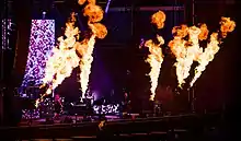 Image d'un groupe de rock jouant au milieu de grandes pyrotechnies