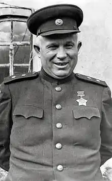 Photographie d'un homme souriant portant un uniforme militaire simple sur lequel est accroché une médaille en forme d'étoile