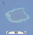 Détail d'une image de la NASA prise en 2003 (à partir de la Station spatiale internationale) de l'île de North Sentinel, la barrière corallienne qui entoure l'île peut être vue clairement. Notez que cette image date d'avant le tsunami de 2004, qui a causé le soulèvement de l'île et l'exposition d'une grande partie du récif.