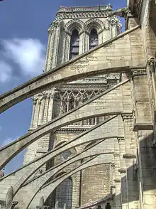 Arc-boutant d'une cathédrale dominés par une tour à section carrée.