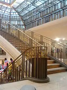 Photographie d'un grand escalier et du toit en verre.