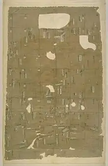 Toile divisée en carrés avec des étiquettes. Une partie de la toile est manquante, laissant des trous dans le tissu.