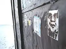 Tag d'une tête styisées en noir sur blanc sur un portail en fer noir. Dessous est marqué Obey.