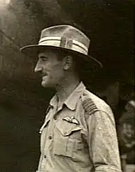 Profil informel tête et torse d'un homme moustachu portant un uniforme clair et un chapeau mou.