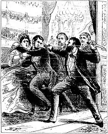 Dans une loge de théâtre, un homme barbu armé d'un couteau dans sa main gauche pointe de sa main droite un pistolet sur la tête du président Lincoln, qui se recule dans les bras de son épouse.