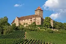 Belle bâtisse, entre le château et la grande maison, au-dessus de vignes.