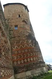 Vue d'une tour et d'un mur, la tour apparaît très oblique.