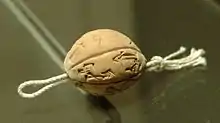 Boule d'argile enfilée sur une cordelette et inscrite de signes cunéiformes.
