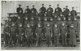Photographie en noir et blancs, où les officiers, en uniforme, portant le képi et l'épée, sont disposés sur quatre rangs.