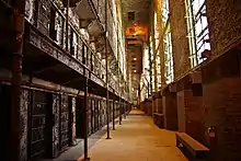 un long couloir de prison avec des cellules sur deux étages du côté gauche.