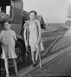 Enfants de réfugiés de la sécheresse de l'Oklahoma sur l'autoroute près de Bakersfield, en Californie. Famille de six personnes ; pas d'abri, pas de nourriture, pas d'argent et presque pas d'essence. L'enfant a une tuberculose osseuse. Juin 1935.