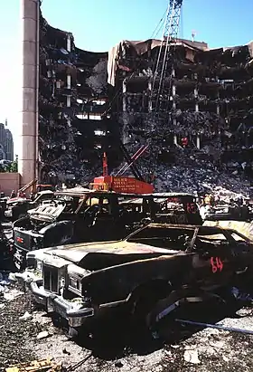 Des voitures brûlées devant les ruines d'un bâtiment dont la façade a été détruite.