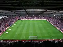 Pelouse verte tondue dans la longueur dans un stade rempli de spectateurs.