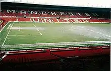 Tribune d'un stade de football avec des sièges rouges sur laquelle est inscrit : « Manchester United »
