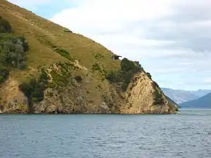 Photographie d'un cap escarpé sur les hauteurs duquel est bâti un bunker en béton.