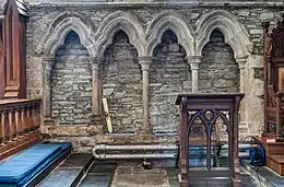 Photographie de quatre niches permettant de s'asseoir, creusées dans le mur intérieur d'une église médiévale.
