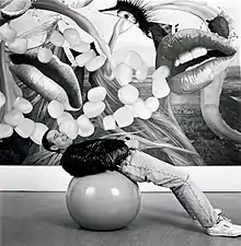 Jeff Koons allongé sur un ballon de gymnastique avec l'une de ses peintures Easyfun.