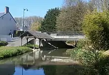 Photographie en couleur d'un pont enjambant un cours d'eau avec un lavoir en contrebas.