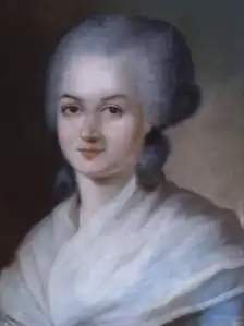 Portrait d'une femme, montrant sa tête, avec une perruque grise. Deux grandes boucles reposent sur la base de son cou. Ses épaules sont couvertes d'un châle léger, de couleur crème.
