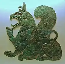 Plaque représentant un animal mi-lion et mi-aigle assis le bec ouvert.