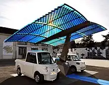 Deux panneaux photovoltaïques faisant de l'ombre à des voitures électriques.