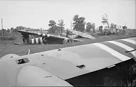 Photo noir et blanc de planeurs démantelés, dans un champ.