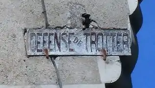Panneau scellé dans un mur et portant l'inscription « DÉFENSE DE TROTTER ».