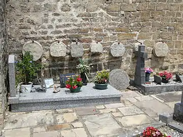 Stèles discoïdales contre le mur du cimetière.